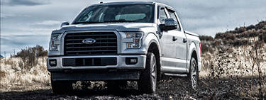 A silver Ford F150 pickup truck traveling through a muddy road