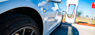 An image of a Tesla vehicle being charged at a charging station.