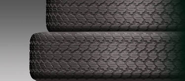 An image of a stack of tires with dollar signs on the tread against a grey background.