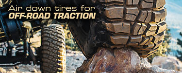 view of the underside of a truck with mud terrain tires rolling over a rock.