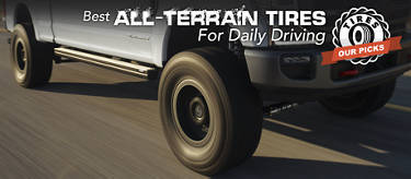 grey truck with all-terrain tires driving down a highway