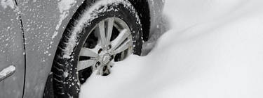 A close up image of a car and the tire deep in snow.