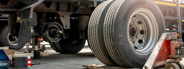 An image of a semi tire next to the underside of a semi truck. 