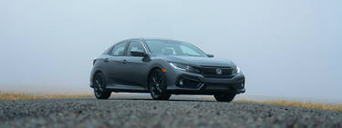 A grey 2015 honda civic parked on the road with a cloudy background