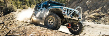 A Jeep Wrangler Rubicon driving down a dusty road.