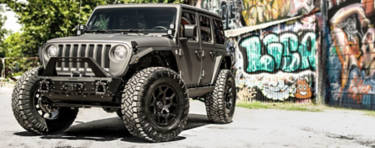 A lifestyle image of a Jeep Wrangler with truck wheels.