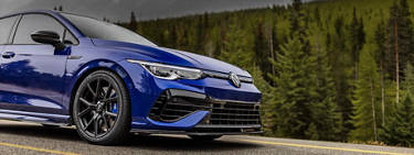 side profile of a VW Jetta with aftermarket wheels driving down a highway with trees in the background