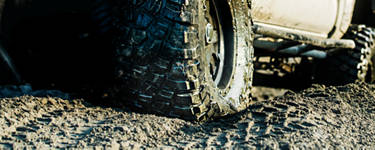 An image of a truck with mud tires rolling through mud.