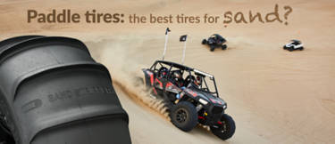 ATV with paddle tires driving over sand dunes