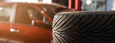 Aftermarket tire stacked next to a red sedan parked in a service bay
