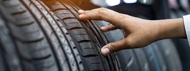 An image of a hand reaching out and touching a tire along a line of many tires.