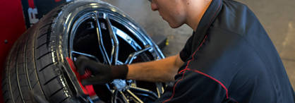 An employee applies tire shine to a tire.'