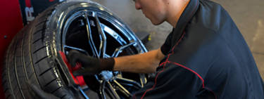 An employee applies tire shine to a tire.