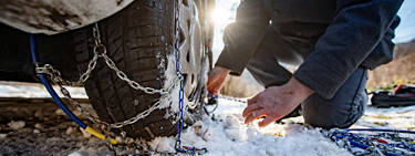 A close up image of some putting tire chains on a vehicle.