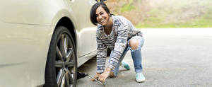 Young woman changing a tire on her car