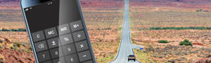 Phone calculator against a pickup truck traveling an open highway in the desert