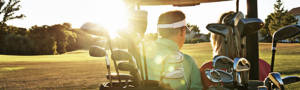 A couple in a golf cart sitting on a sunny hillside