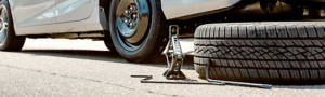 Car on side of the road with a jack and a spare tire