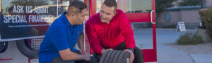 Sales associate explaining tire dimensions to a customer outside a Discount Tire store