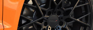 close up of a gloss black wheel on an orange sports car