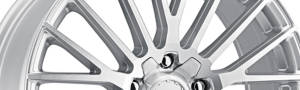 close up of the face of a silver aftermarket car wheel on a white background