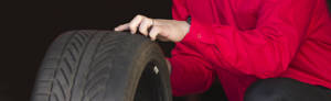 an America's Tire employee in a red shirt analyzes a tire.