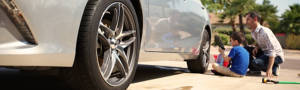 Dad and son cleaning the tires on the family car