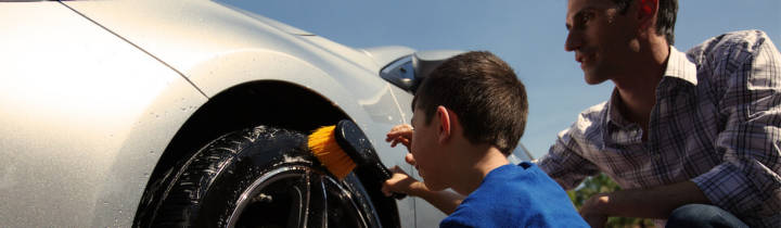 Father and son scrubbing the side wall of a tire with a tire brush