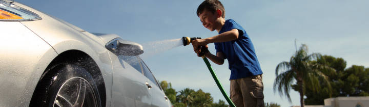 Child spraying tire with a hose