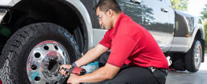 Technician unbolting a wheel assembly from a truck