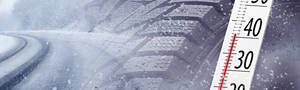 Snow tire in the snow next to a thermometer displaying colder than 45 degrees F