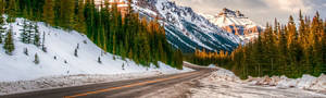 a plowed road through snow covered mountains