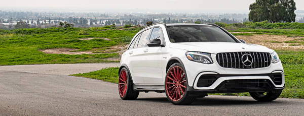 White Mercedes sedan featuring aftermarket red multi-spoke wheels