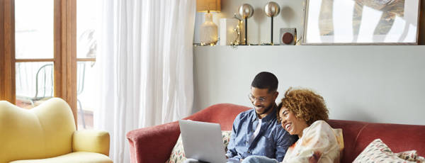 Happy couple on a sofa working on a laptop