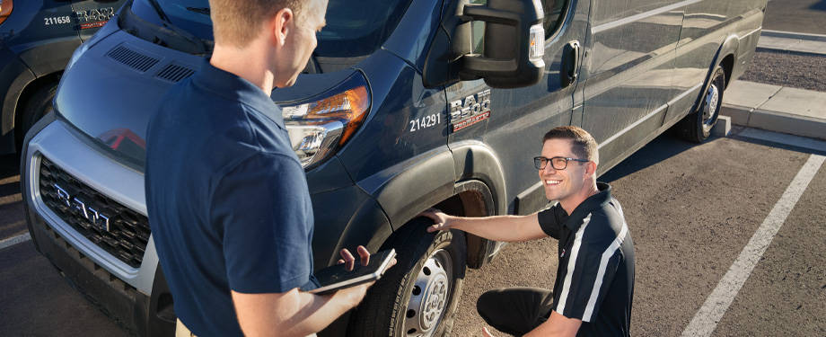 Fleet tech with a fleet customer inspecting tire on a van