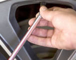 Close up of hand using tire gauge to check tire air pressure.