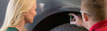 An America's Tire employee and a woman inspect a tire.