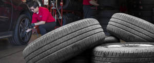 America's Tire employee in the process of replacing tires with a stack of tires in the foreground