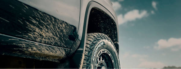 Vehicle driving on muddy path with Cooper Tires