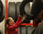 Store associate storing a tire on a large tire rack