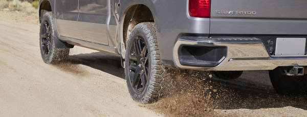 Goodyear Wrangler DuraTrac RT tires spitting rocks on a dirt road via a Chevy Silverado