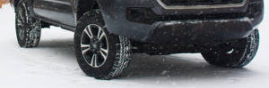 a truck with all-terrain tires driving through a snowy road