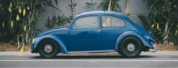 Blue VW Beatle parked on the side of the road with Mobelwagen aftermarket wheels.