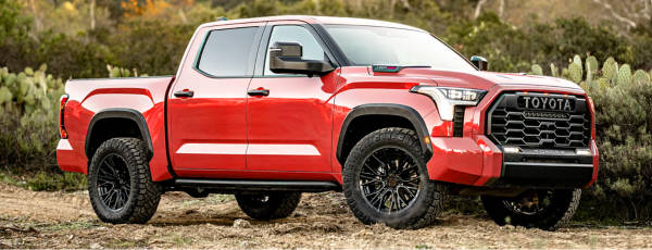 Red Toyota Tundra with MTX wheels parked on a dirt road.