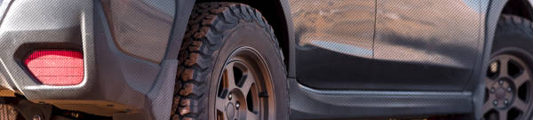 A close up of an SUV with bronze wheels parked on the side of the road.
